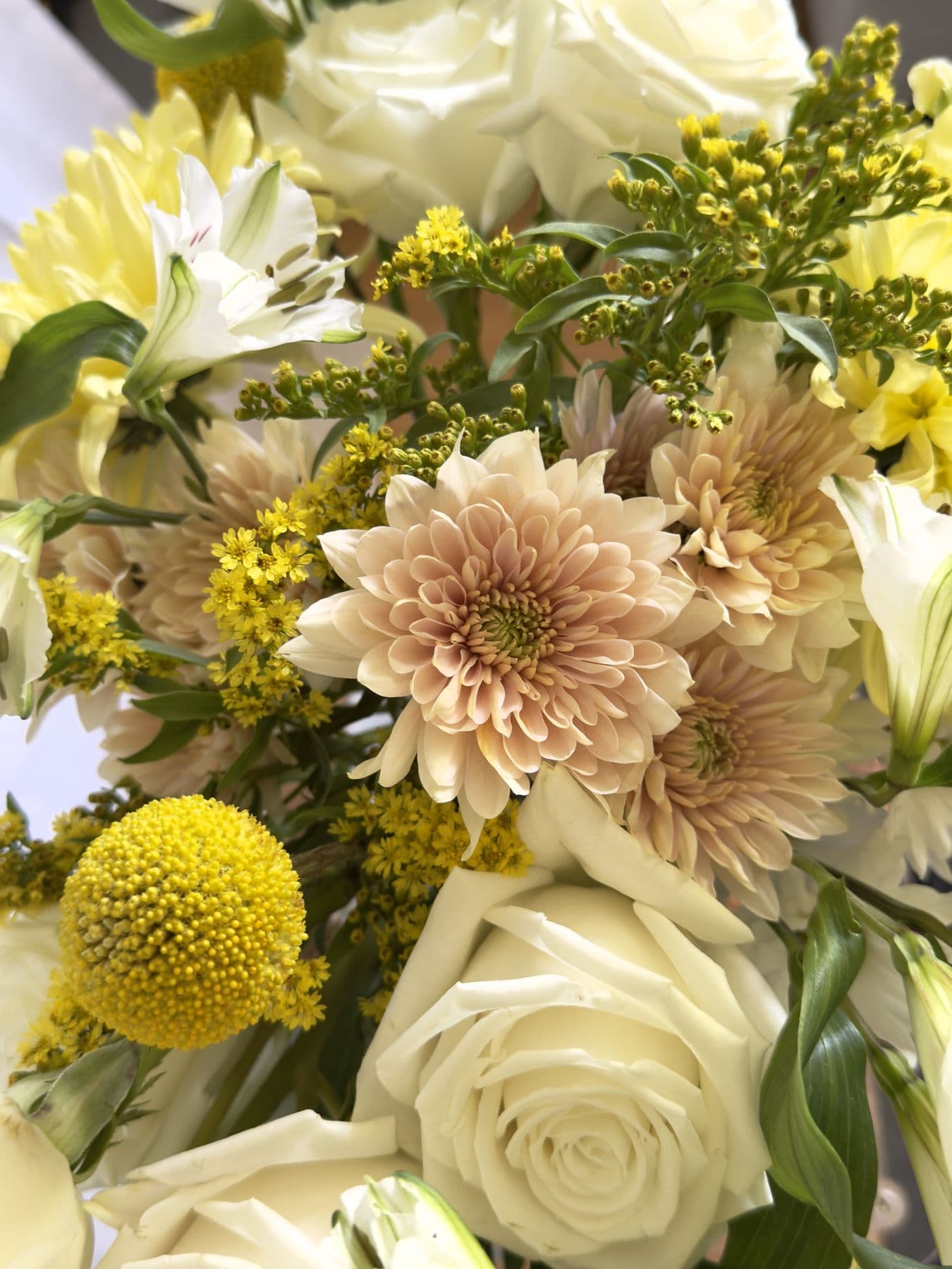 Close view of café-au-lait chrysanthemums, cream roses, and goldenrod