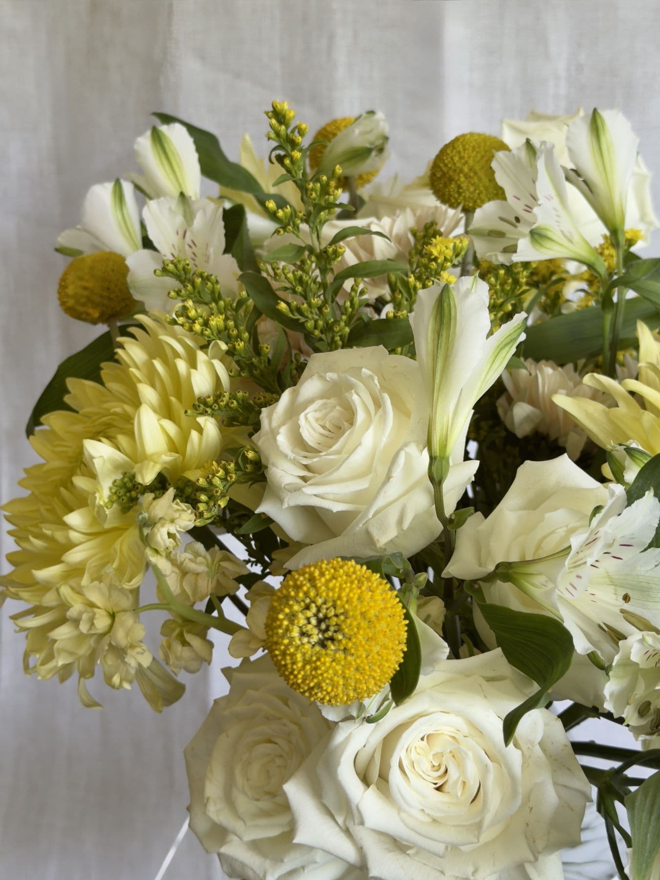 Close view of white roses, yellow billy balls, and alstroemeria